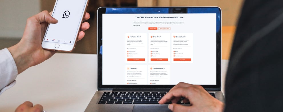 Whatsapp icon on an iphone next to the Hubspot interface on a laptop